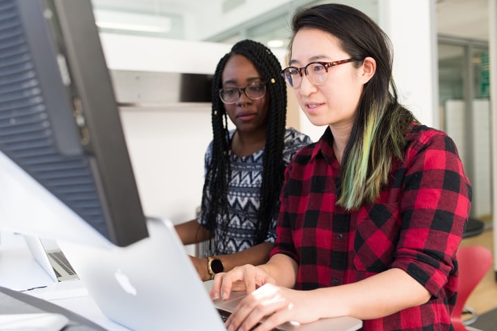Deux femmes regardent attentivement l'écran d'un ordinateur portable dans un bureau