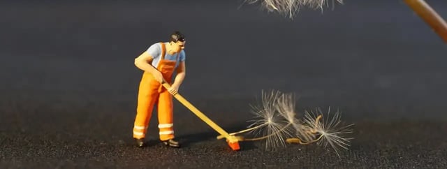 Figurine d'un balayeur en tenue orange poussant des graines de pissenlit avec un balai, image du nettoyage de données