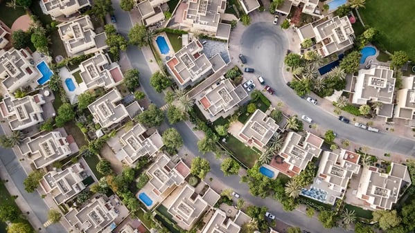 Vue aérienne d'un quartier résidentiel de maisons modernes avec jardins, piscines et rues arborées